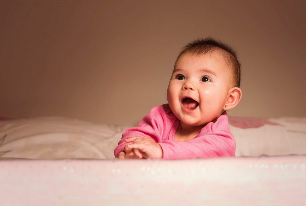 smiling baby lying on bed in room 1557182 scaled 1